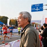 某省级体育赛事运营公司总经理，五十岁左右，短发灰白，穿着休闲夹克，背景是马拉松赛事现场